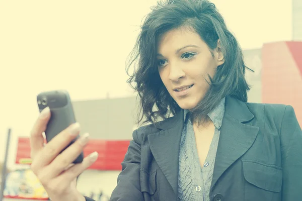 ウォーキング、blured ビジネス建物の携帯電話を持つ若い女 — ストック写真