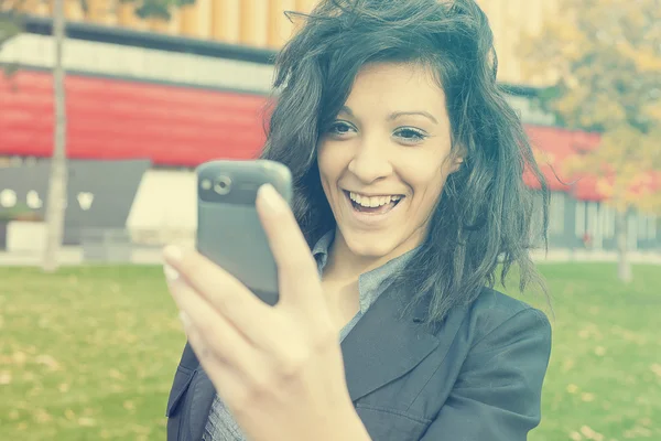 Jonge vrouw met grappige haar glimlach met behulp van mobiele telefoon wandelen — Stockfoto