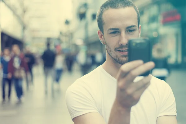 Giovane con cellulare a piedi — Foto Stock