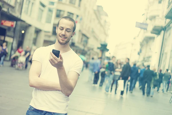 Hombre joven con teléfono celular caminando en la ciudad — Foto de Stock