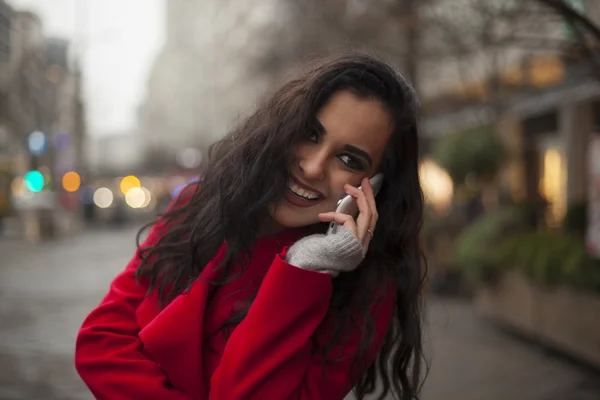 Mulher sorridente bonita em casaco vermelho com telefone celular nas mãos , — Fotografia de Stock