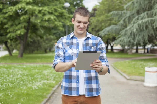 Hombre con Tablet PC en el parque, las redes sociales en ewery lugar — Foto de Stock