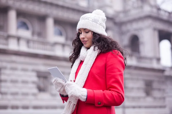 Woman in red coat and wool cap and gloves with smartphone in han — Stock Photo, Image