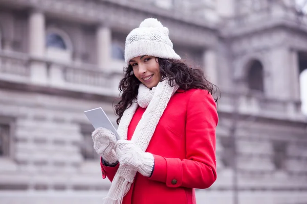 Hermosa mujer en abrigo rojo y gorra de lana y guantes con smartph — Foto de Stock