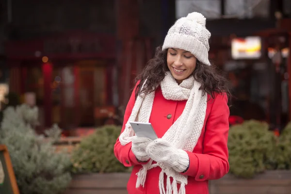 Kırmızı ceket ve yün şapka ve eldiven smartph ile güzel kadın — Stok fotoğraf