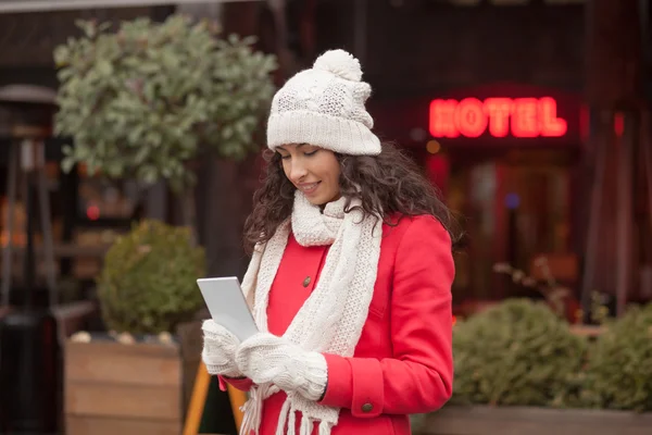 Vacker kvinna i röd kappa och ull mössa och handskar med smartph — Stockfoto