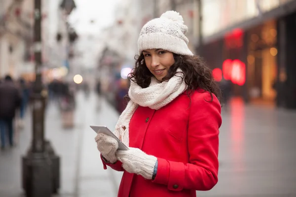 Kvinna i röd kappa och ull mössa och handskar med smartphone i han — Stockfoto
