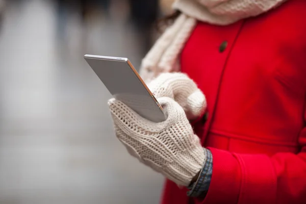 Frau in Wollhandschuhen hält Smartphone in der Hand — Stockfoto