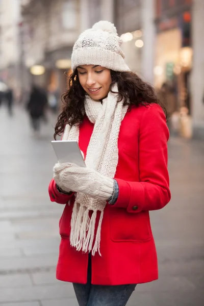 Kvinna i röd kappa och ull mössa och handskar med smartphone i han — Stockfoto