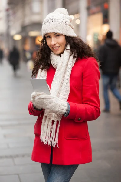Kvinna i röd kappa och ull mössa och handskar med smartphone i han — Stockfoto