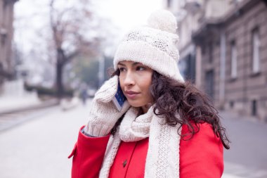 Güzel kız kırmızı ceket ve yün şapka ve eldiven smartpho ile