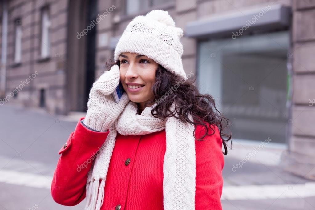 Woman in red coat and wool cap and gloves with smartphone in han Stock
