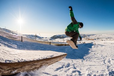 Mavi gökyüzüne atlayan snowboardcu