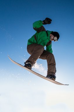 Mavi gökyüzüne atlayan snowboardcu