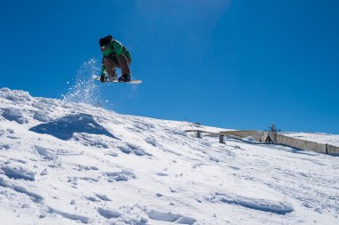 Mavi gökyüzüne atlayan snowboardcu