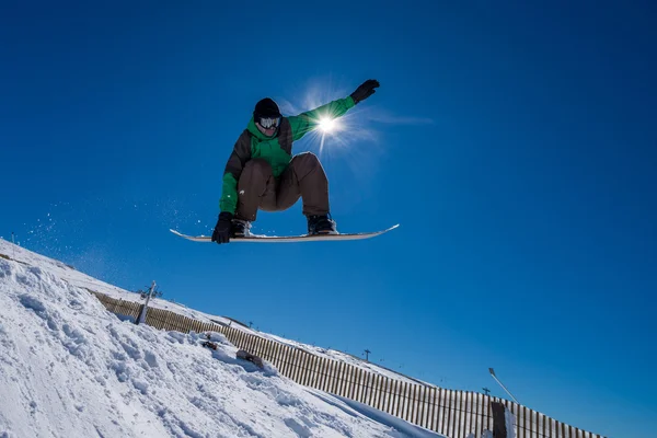 Snowboarder hoppe mod blå himmel - Stock-foto