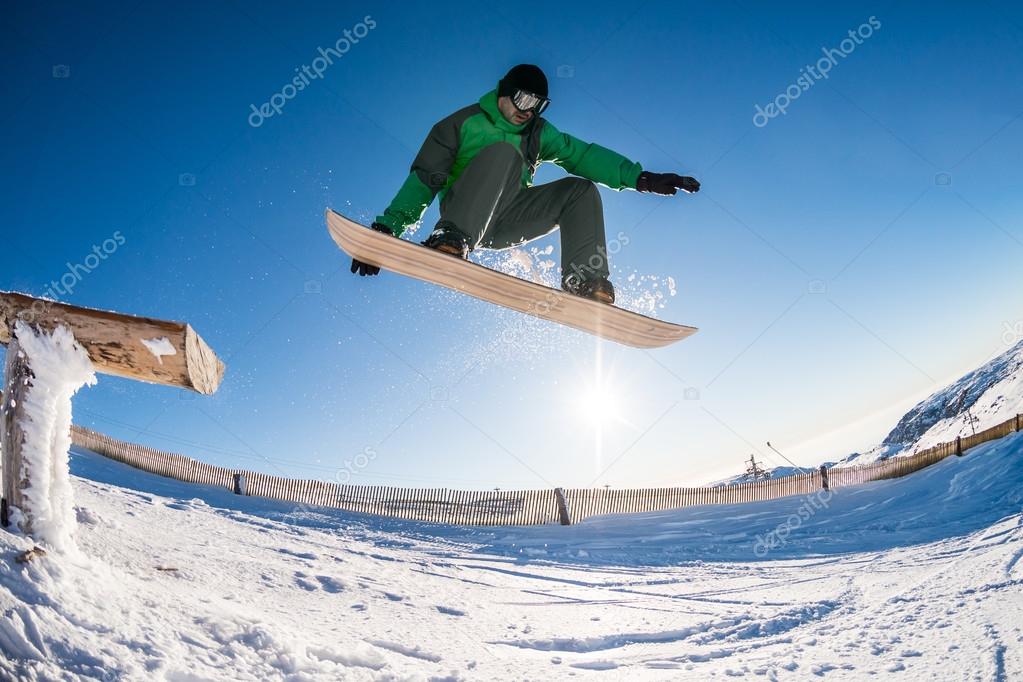 Snowboarder jumping against blue sky