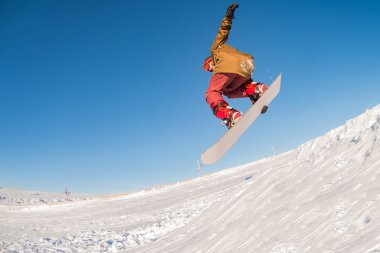 Mavi gökyüzüne atlayan snowboardcu