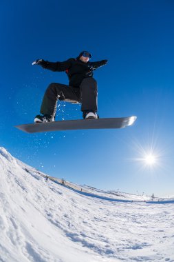 Mavi gökyüzüne atlayan snowboardcu