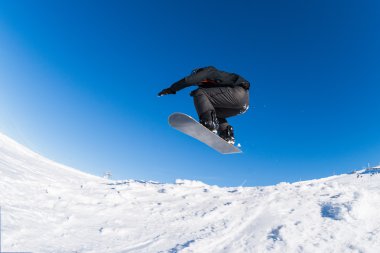 Mavi gökyüzüne atlayan snowboardcu