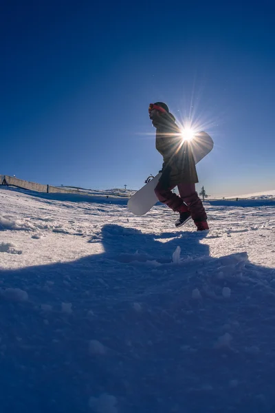 Snowboardzista spaceru przeciw błękitne niebo — Zdjęcie stockowe