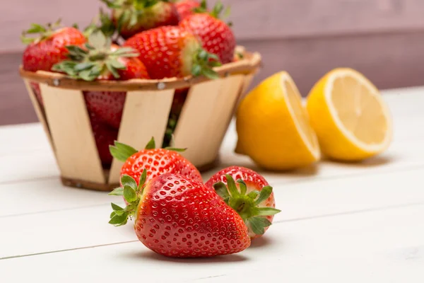 Strawberries in a small basket and lemon — Stock Photo, Image