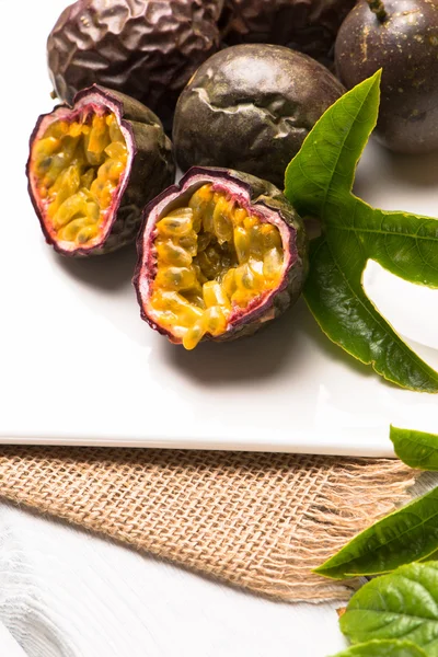 Frutas de la pasión en bandeja de cerámica blanca sobre fondo de mesa de madera . — Foto de Stock