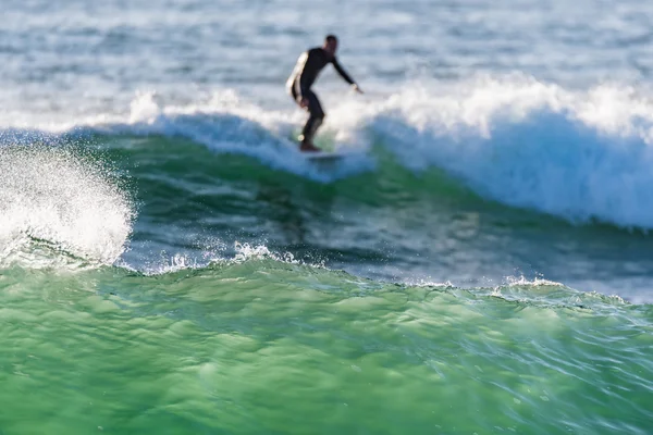 Larga tabla surfeando las olas al atardecer — Foto de Stock