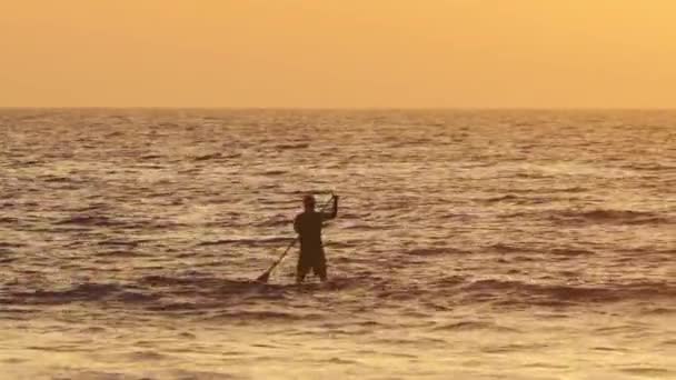 Silhouette de pagayeur debout au coucher du soleil 