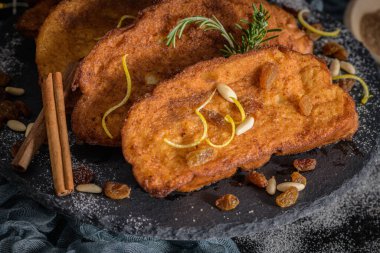 Traditional Christmas Rabanadas with lemon zest, raisins, pine nuts and cinnamon. Spanish Torrijas or french toasts close up on the countertop