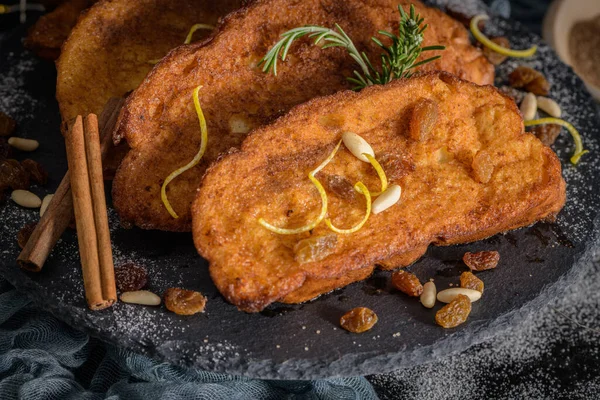 Traditional Christmas Rabanadas with lemon zest, raisins, pine nuts and cinnamon. Spanish Torrijas or french toasts close up on the countertop