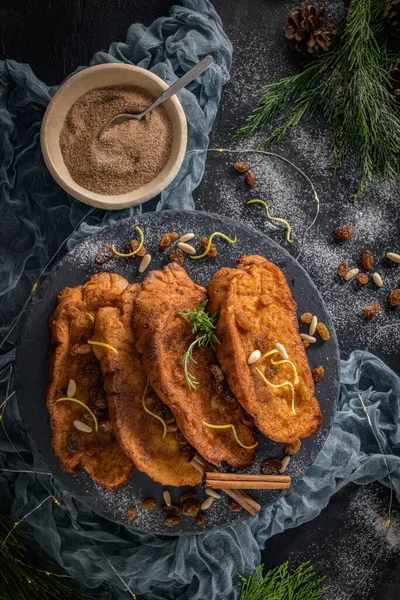 Traditional Christmas Rabanadas with lemon zest, raisins, pine nuts and cinnamon. Spanish Torrijas or french toasts close up on the countertop