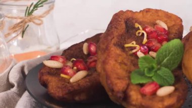 Traditional Christmas Rabanadas with pommegranate seeds, pine nuts and cinnamon. Spanish Torrijas or french toasts close up on the countertop.