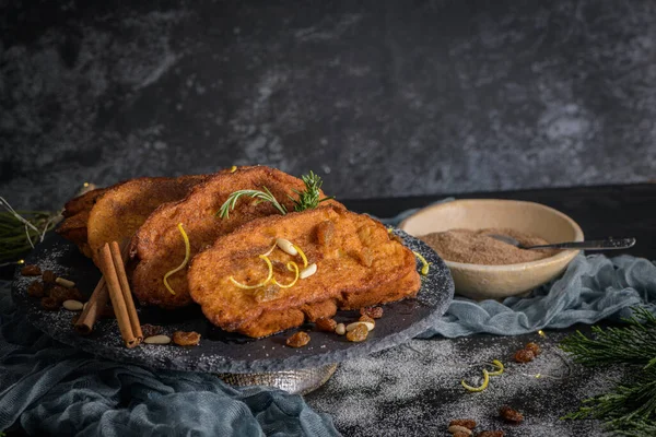 Traditional Christmas Rabanadas with lemon zest, raisins, pine nuts and cinnamon. Spanish Torrijas or french toasts close up on the countertop