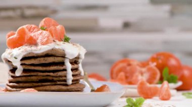 Yulaf, kekik ve nane yapraklarıyla modern mutfak tezgahında yoğurt ve mandalinalı krep..