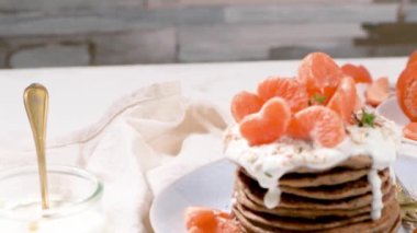 Yulaf, kekik ve nane yapraklarıyla modern mutfak tezgahında yoğurt ve mandalinalı krep..