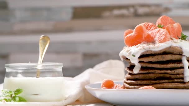 带有酸奶和橘子的薄饼放在一个轻便的现代厨房柜台上 上面有燕麦 百里香和薄荷叶 — 图库视频影像