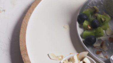 Kivili Chia pudingi, yabanmersini ve hindistan cevizi dilimleri, beyaz bir masada cam kavanozlarda üç porsiyon..