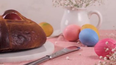 Masanın üstünde yumurta ve pembe masa örtüsü olan Paskalya folar..