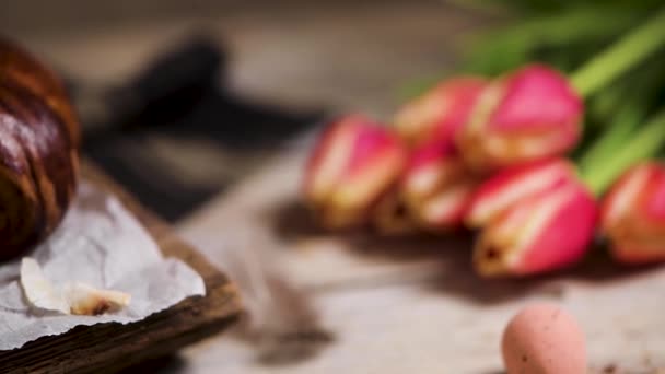ポルトガルの伝統的なイースターケーキ イースターテーブルの上の卵で葉っぱ 花チューリップ カラフルな絵の卵と羽 — ストック動画