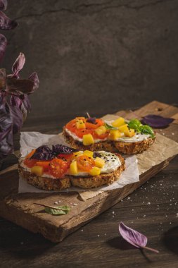 Kızarmış domatesli İtalyan bruschetaları, mozzarella peyniri, ananas dilimleri ve tahta kesme tahtasındaki otlar..