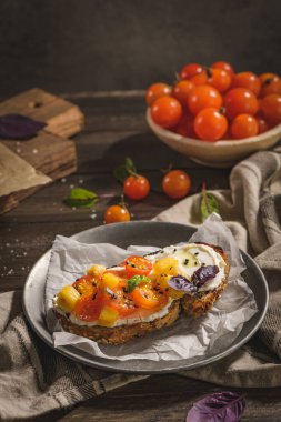 Kızarmış domatesli İtalyan bruschetta, mozzarella peyniri, ananas dilimleri ve metal bir tabakta otlar..