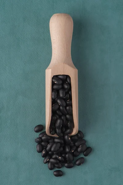 Wooden scoop with black beans — Stock Photo, Image