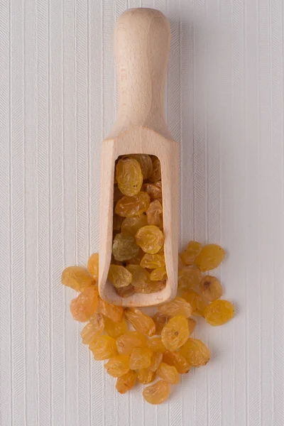 Wooden scoop with golden raisins — Stock Photo, Image