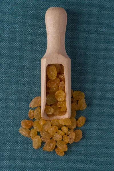 Wooden scoop with golden raisins — Stock Photo, Image