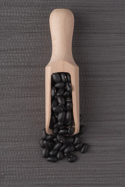 Wooden scoop with black beans — Stock Photo, Image