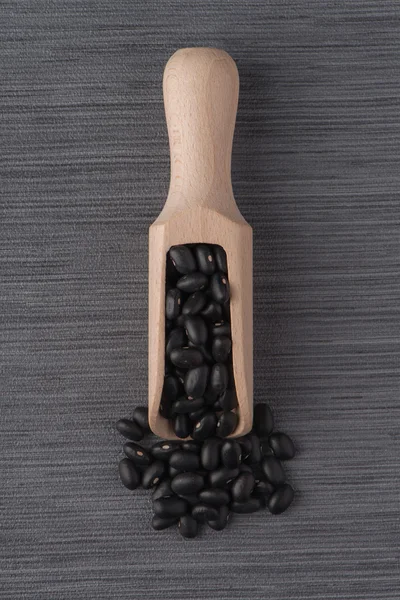 Wooden scoop with black beans — Stock Photo, Image