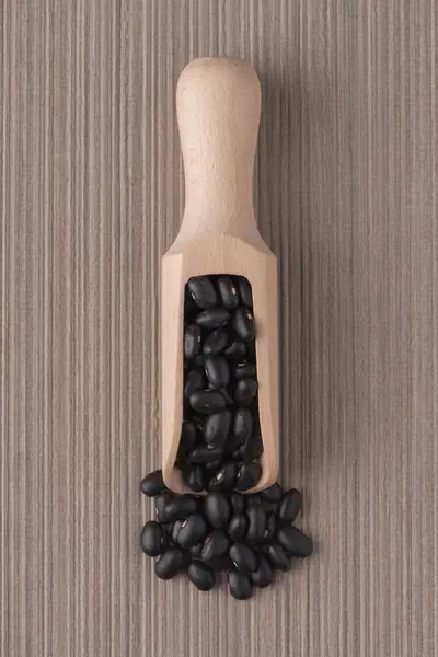 Wooden scoop with black beans — Stock Photo, Image