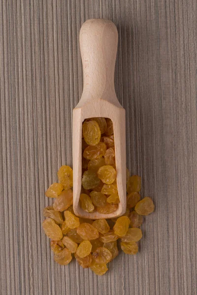 Wooden scoop with golden raisins — Stock Photo, Image