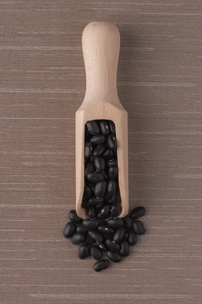 Wooden scoop with black beans — Stock Photo, Image